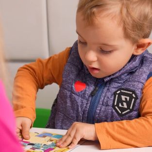 Дете се усмихва и показва увереност по време на терапевтична сесия, развивайки самочувствие и личностни умения.